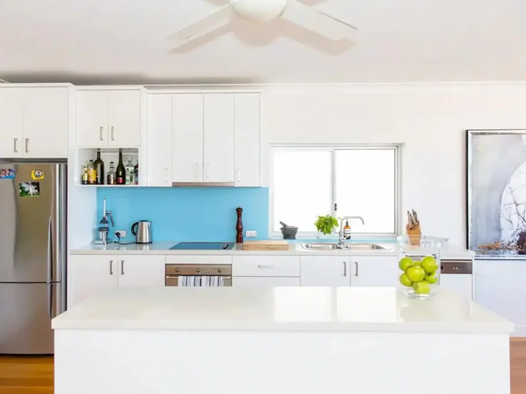 Kitchen with a bright blue splashback and white island in a Bronte Airbnb managed by AU Smart Rentals