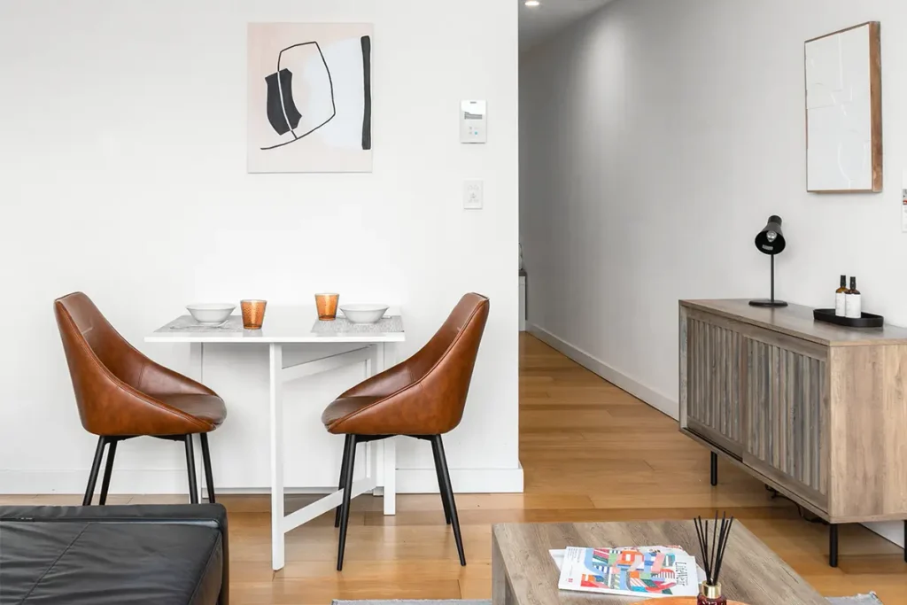 Living area with a TV unit, work desk and yellow accents in a furnished Randwick apartment